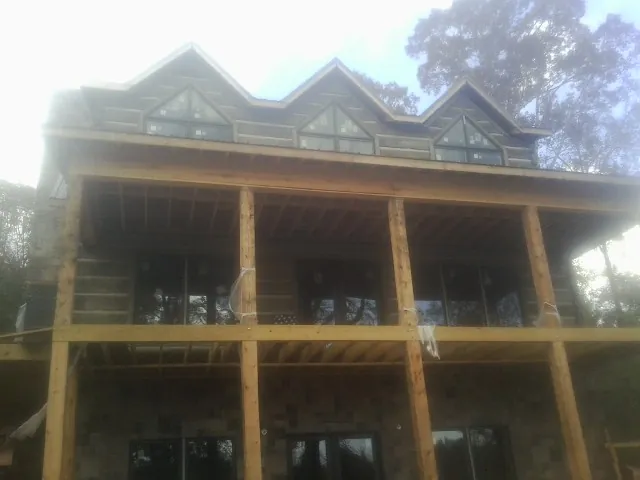 Dormers and porch framing on a large log home under construction — Roof Coating work by our crew in Cohoes