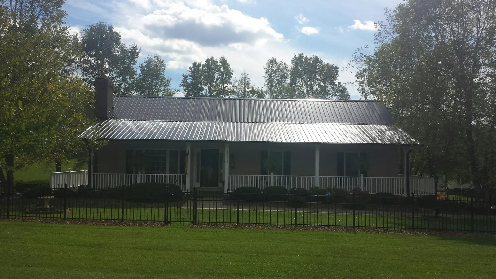 Gray metal roof on a brick ranch with a full width front porch — Gutter Guard Installation work by our crew in Cohoes