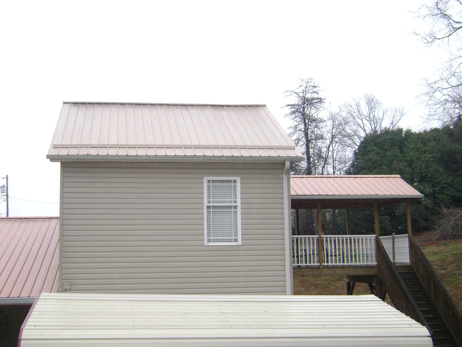 Tan metal roofs on a two story addition and attached porch, from a Roof Replacement job in Cohoes