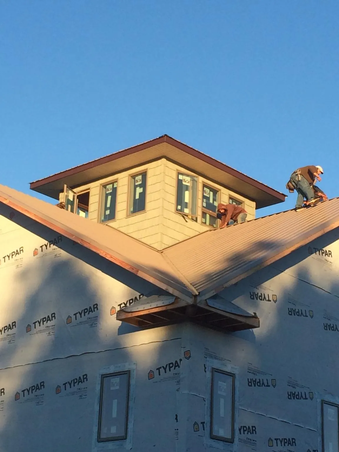 Roofers working around a rooftop cupola on a new metal roof at sunset — Roof Waterproofing in Cohoes by Roofing Brothers